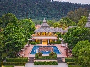 A resort with a swimming pool, multiple buildings with thatched roofs, and lush greenery.