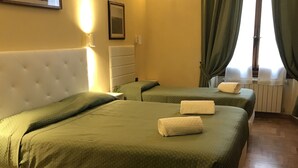 A hotel room with two beds, a large window with curtains, a radiator, and a wall-mounted light fixture. - Hotel Giglio (Florence)