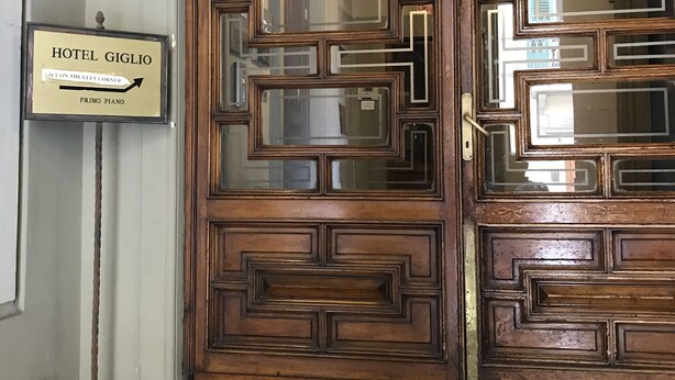 A wooden hotel entrance with a sign indicating the location of the first piano. - Hotel Giglio (Florence)