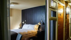 A hotel room with a bed, bedside tables, a lamp, and a small table with a cup and saucer.