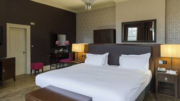 Une chambre d’hôtel avec un grand lit, des lampes de chevet, un bureau, une chaise, une armoire et un miroir.