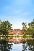 A large brick building with a reflective pond in front.
