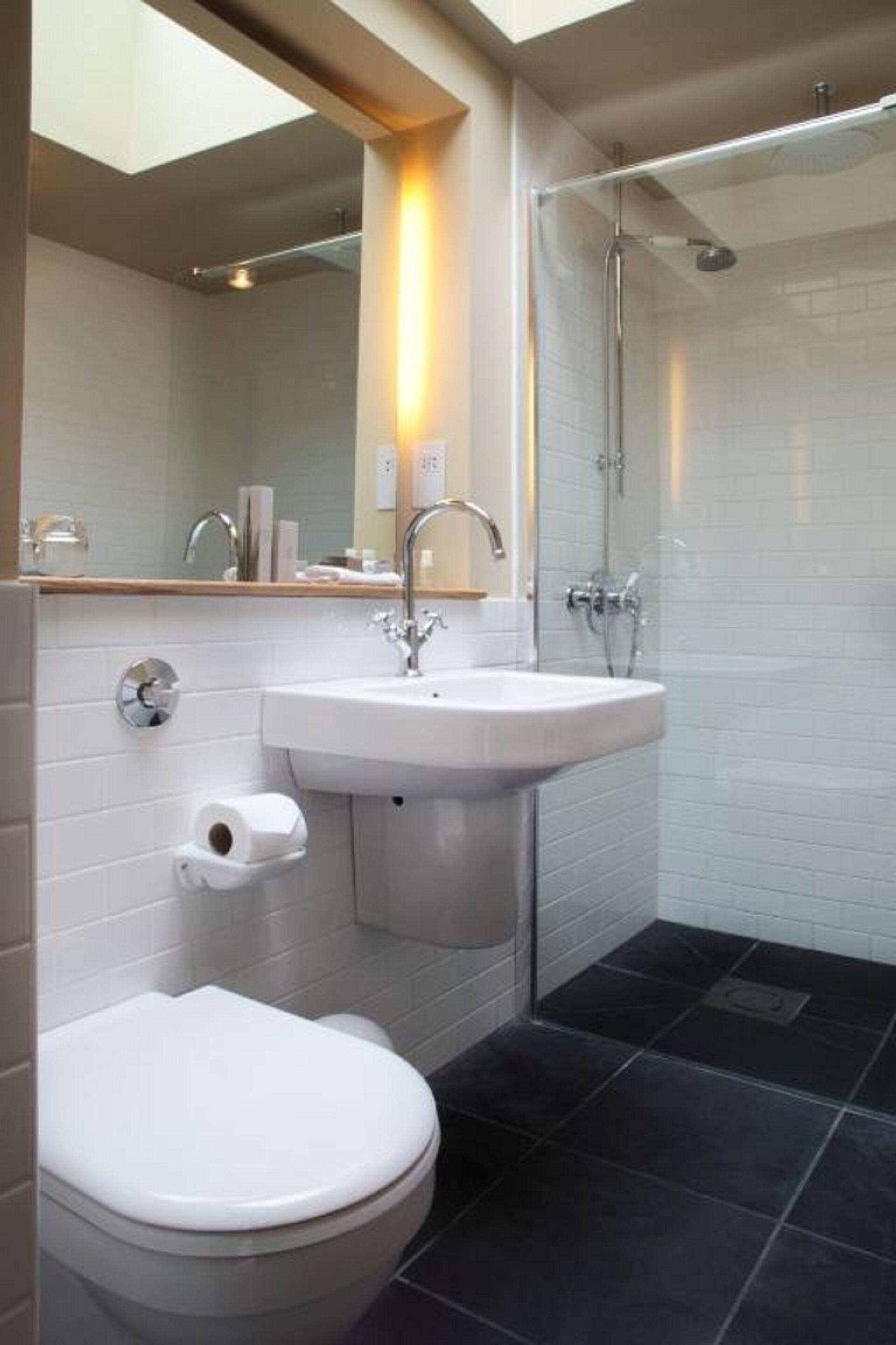 Un baño moderno con inodoro, lavamanos y ducha.