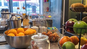 Un bufé de desayuno con diversas frutas, bollería y bebidas.