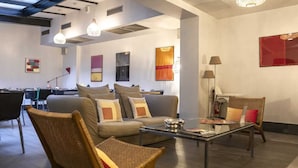 Una sala de estar moderna con un sofá, sillas, una mesa de centro de vidrio y obras de arte en las paredes.