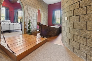 A room with a wooden swing, a small potted plant, and a bathtub. - Chateau Avalon Hotel & Spa (Kansas City)