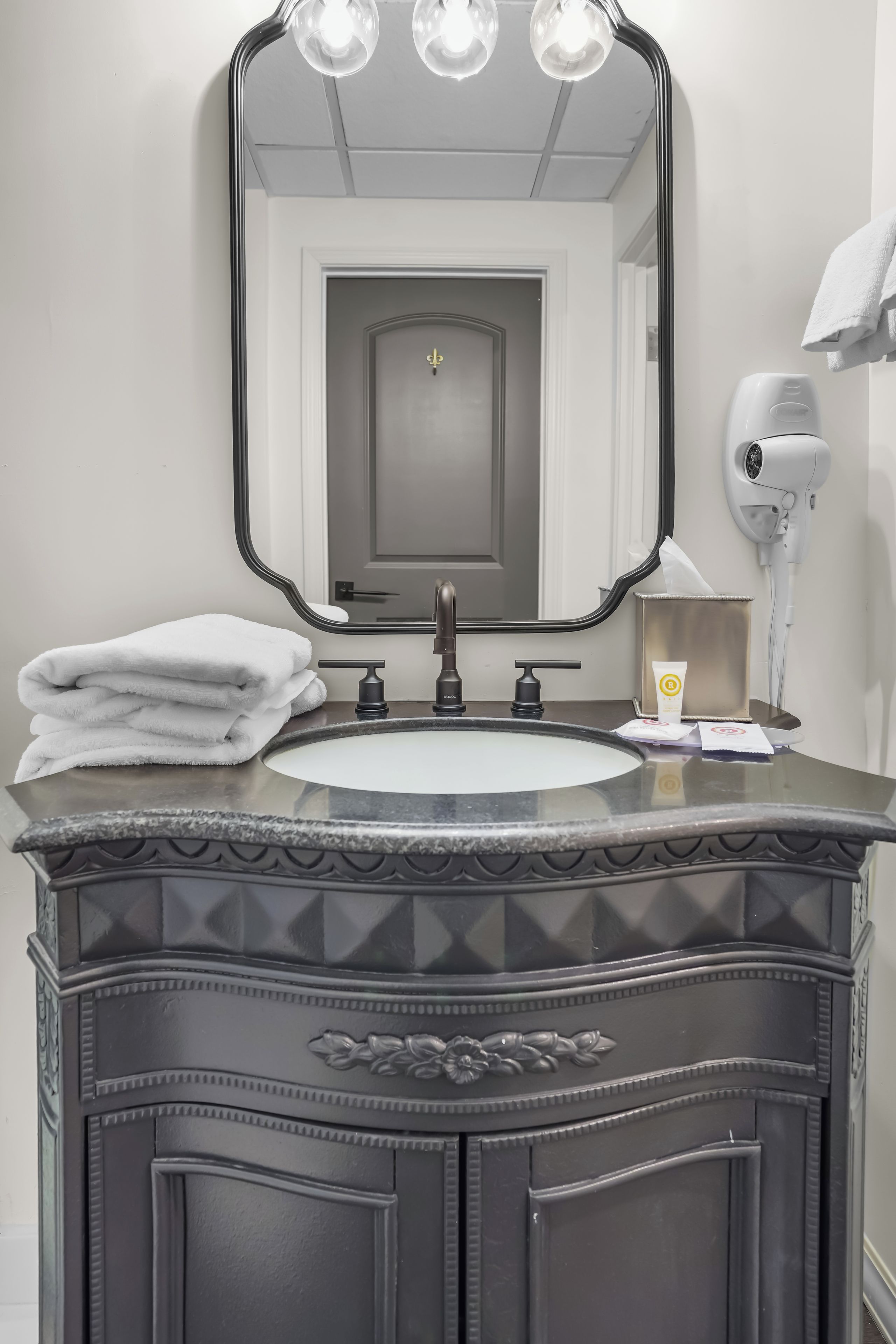 Un mueble de baño con espejo, lavabo y perchero para toallas.