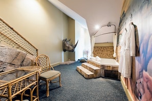 A room with a large wall-mounted rhinoceros head, a bathtub, a chair, and a staircase. - Chateau Avalon Hotel & Spa (Kansas City)