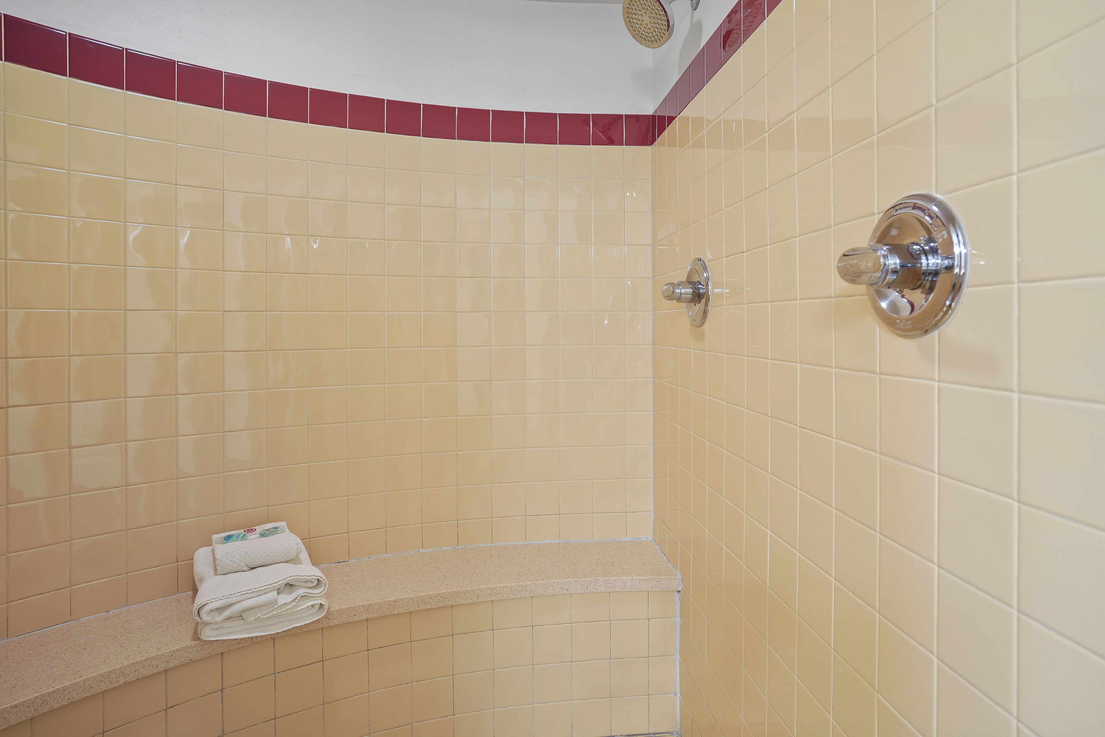 A tiled shower area with a towel rack and a showerhead.