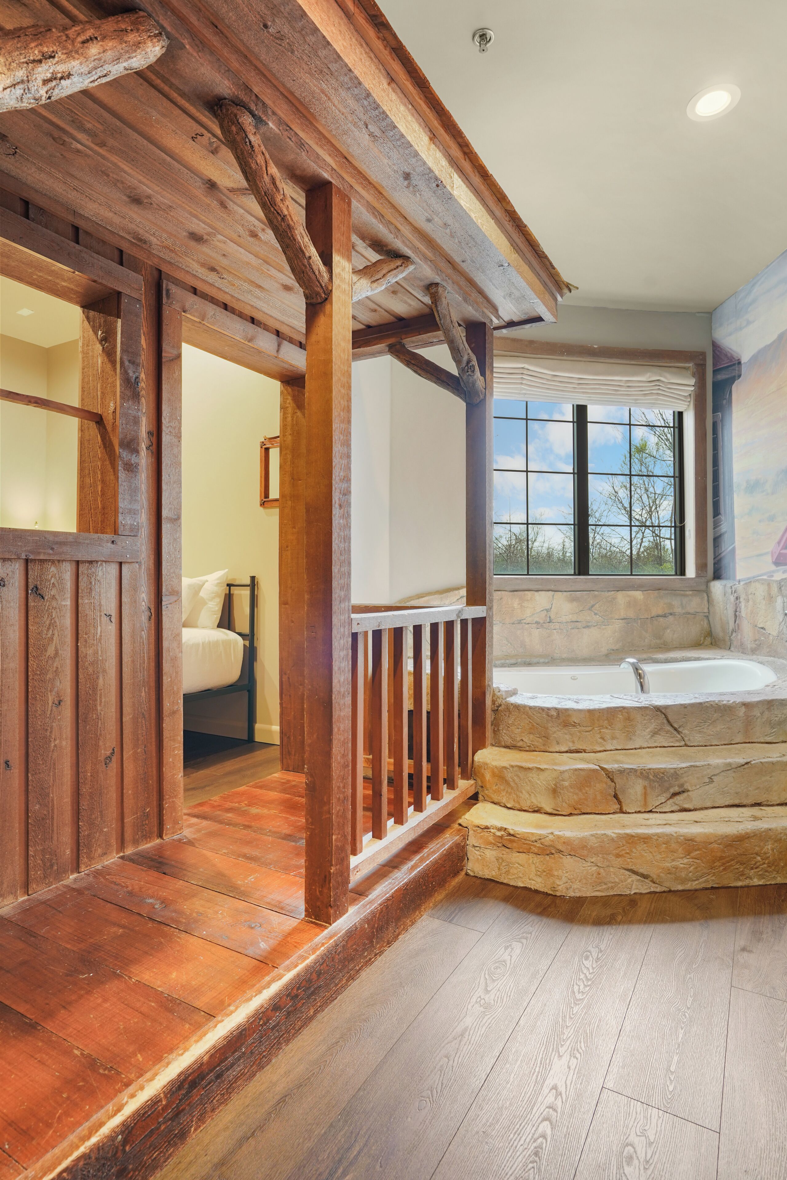 A wooden interior with a stone bathtub, a wooden staircase, and a bed.
