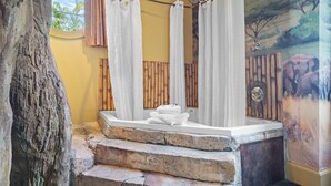 A bathroom with a stone bench, a bathtub, and a shower curtain. - Chateau Avalon Hotel & Spa (Kansas City)