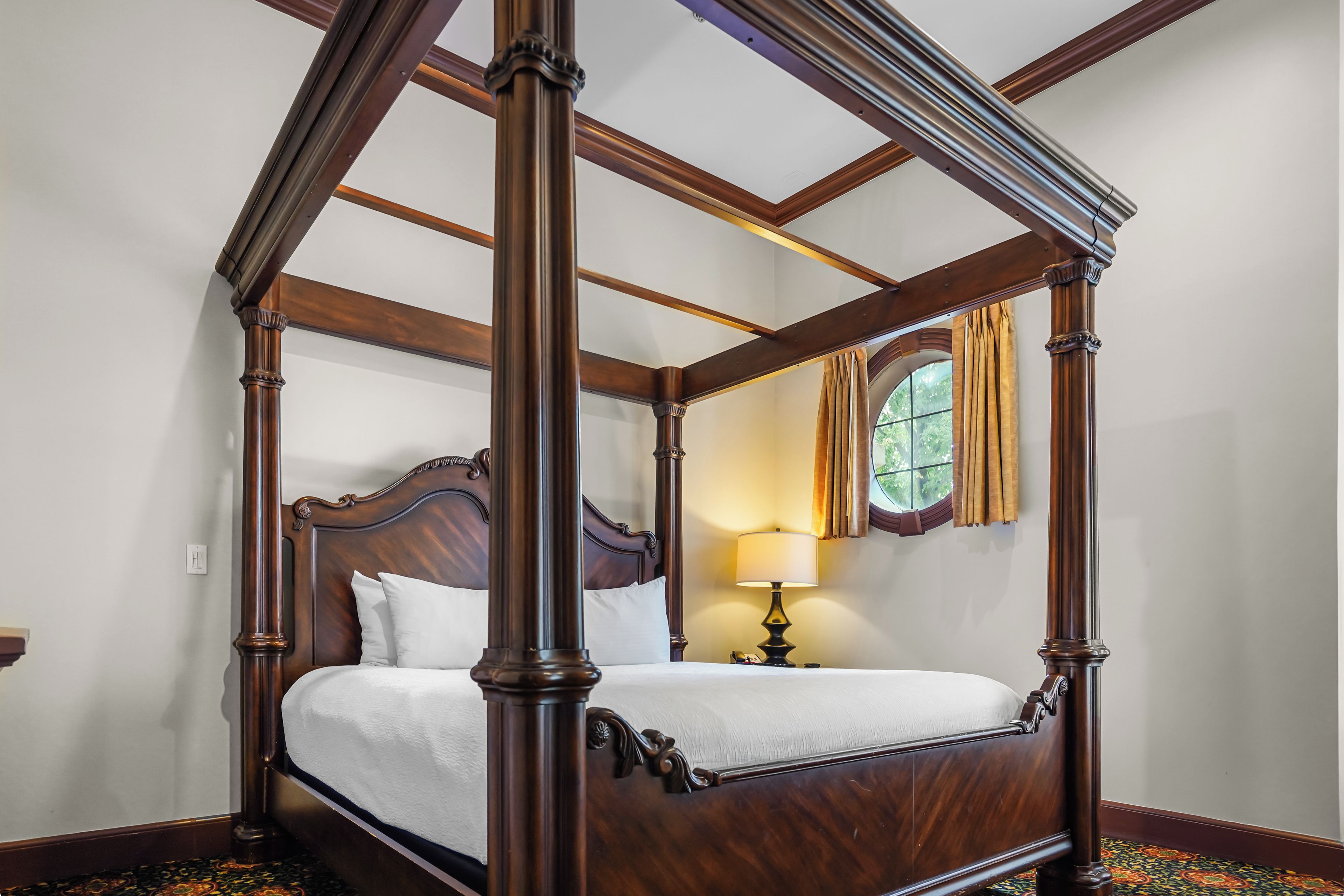 A four-poster bed with a wooden frame and white bedding.