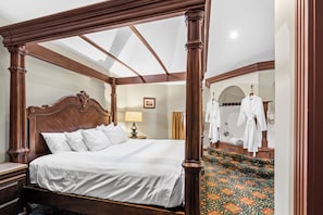 A four-poster bed with a wooden headboard, white bedding, a bedside table, and a lamp. - Chateau Avalon Hotel & Spa (Kansas City)