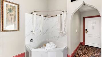 Un baño con bañera de mármol, ducha y toallero.