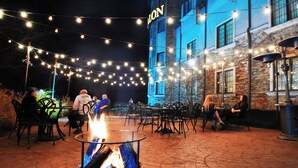 An outdoor seating area with string lights, a fire pit, and tables and chairs. - Chateau Avalon Hotel & Spa (Kansas City)
