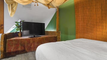 A room with a bed, a television on a wooden bench, and a green wall.