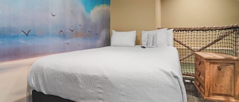 Una habitación de hotel con una cama grande, un mural en la pared y una mesita de noche de madera.
