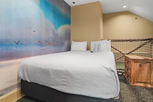 Una habitación de hotel con una cama grande, un mural en la pared y una mesita de noche de madera.
