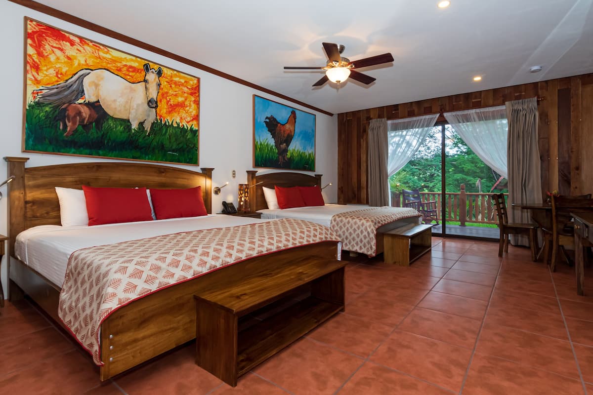A hotel room with two beds, a ceiling fan, and large windows with curtains.