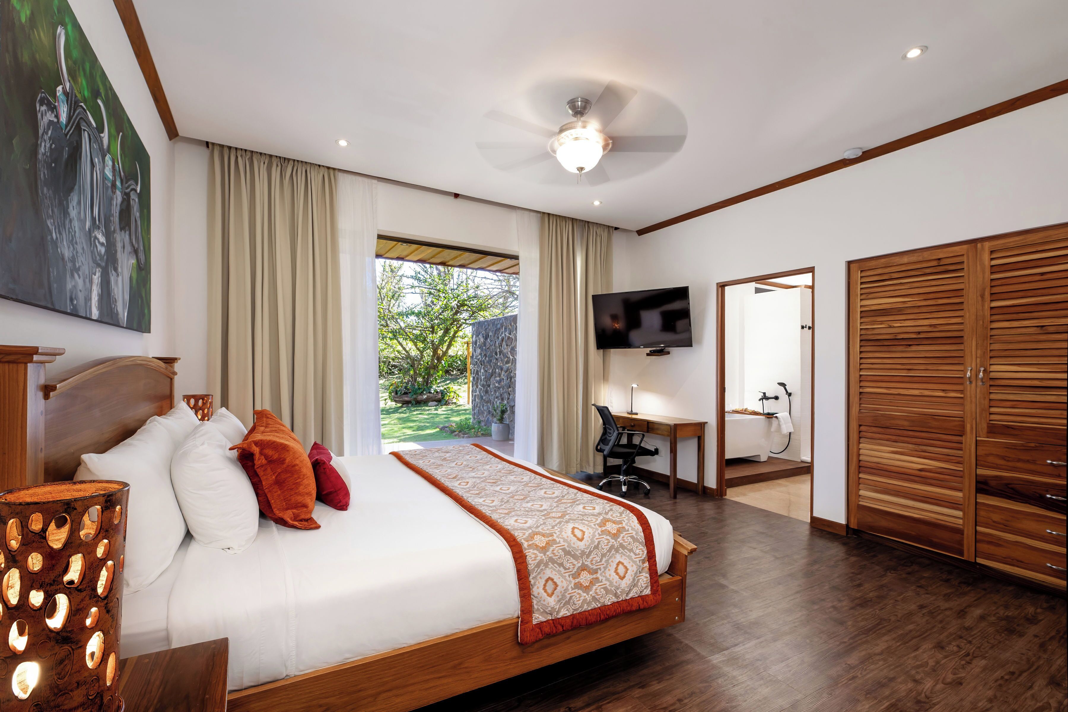 Una habitación de hotel moderna con una cama grande, un escritorio, un televisor y un armario.
