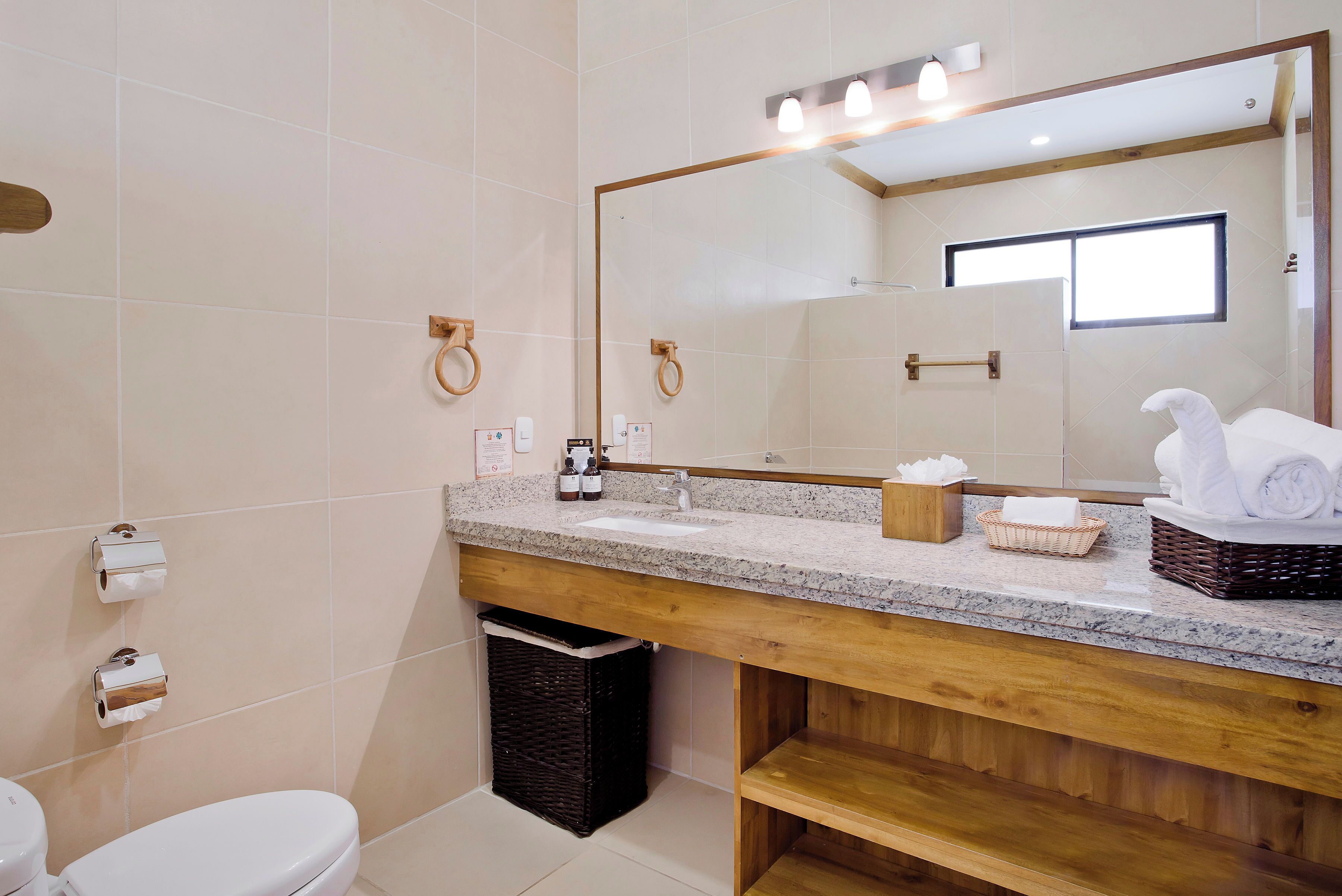 Un bagno moderno con un mobile bagno in legno, uno specchio grande e un water.