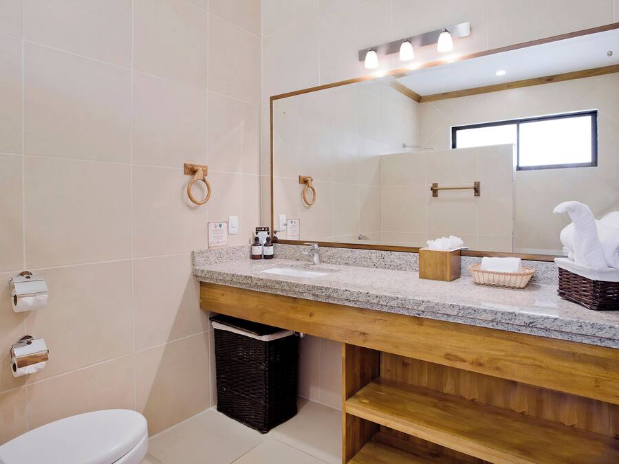 Un bagno moderno con un mobile bagno in legno, uno specchio grande e un water.