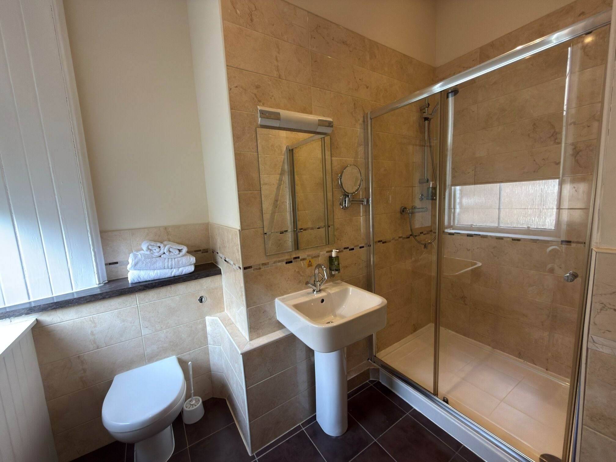 A modern bathroom with a toilet, sink, and glass-enclosed shower.