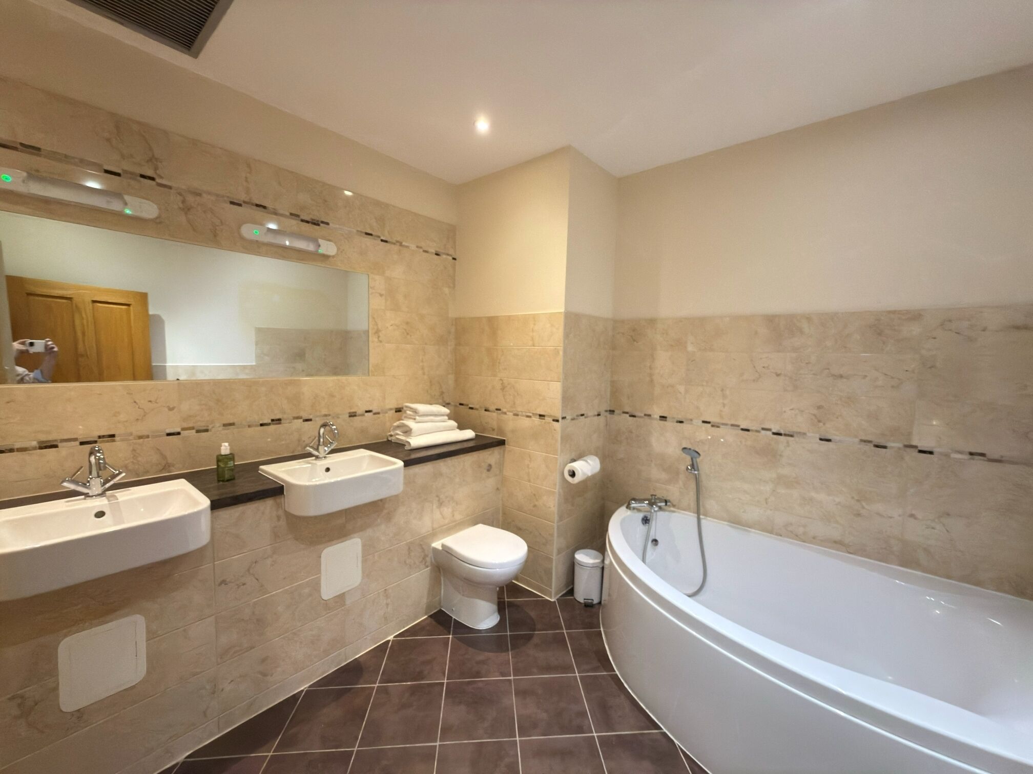 A bathroom with a bathtub, two sinks, a toilet, and a mirror.