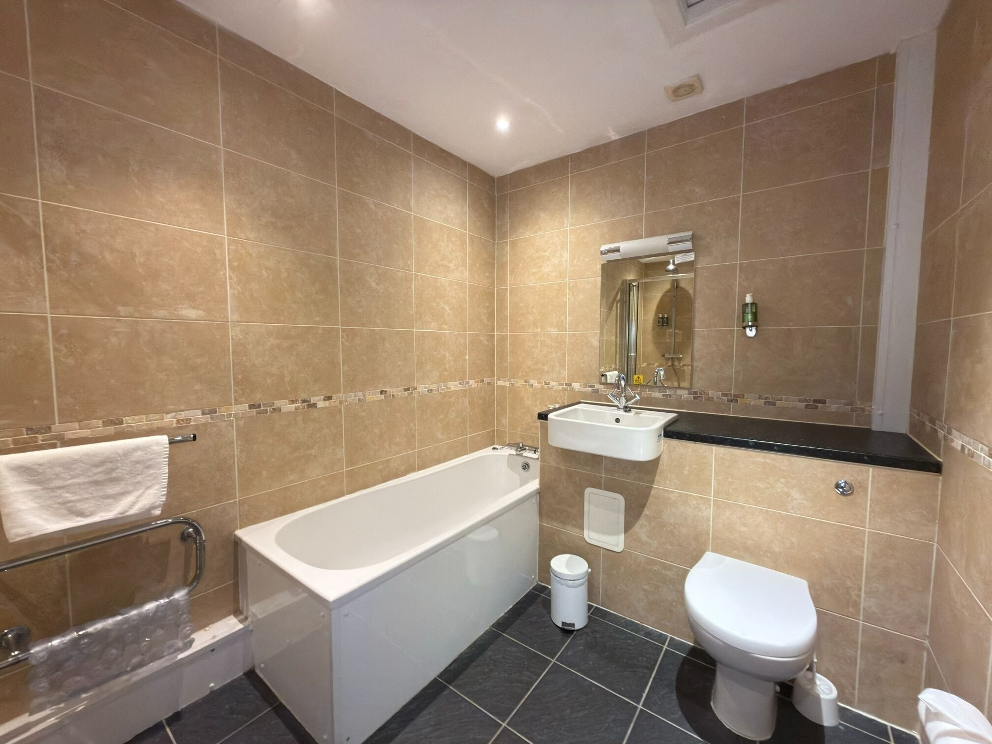 A bathroom with a bathtub, sink, toilet, and a mirror.