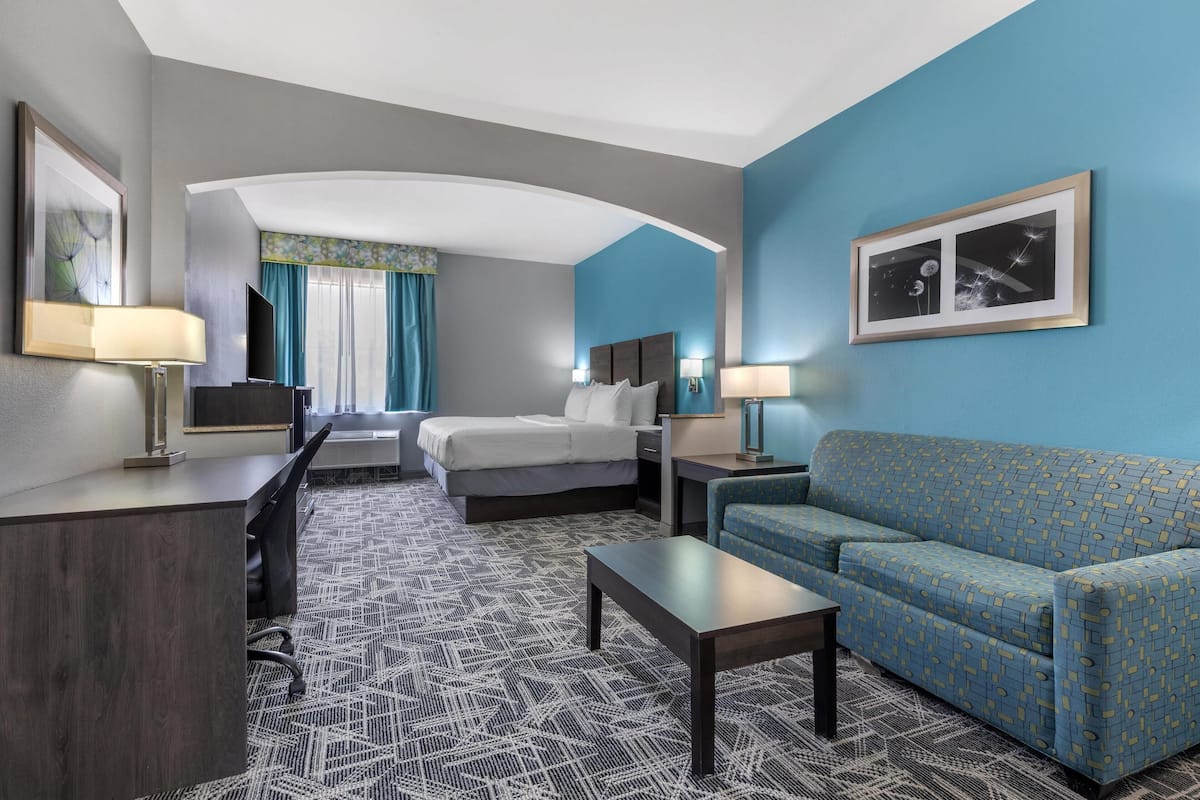 Ein Hotelzimmer mit Bett, Sofa, Schreibtisch und Fernseher.