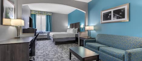 A hotel room with a bed, a sofa, a desk, and a TV.
