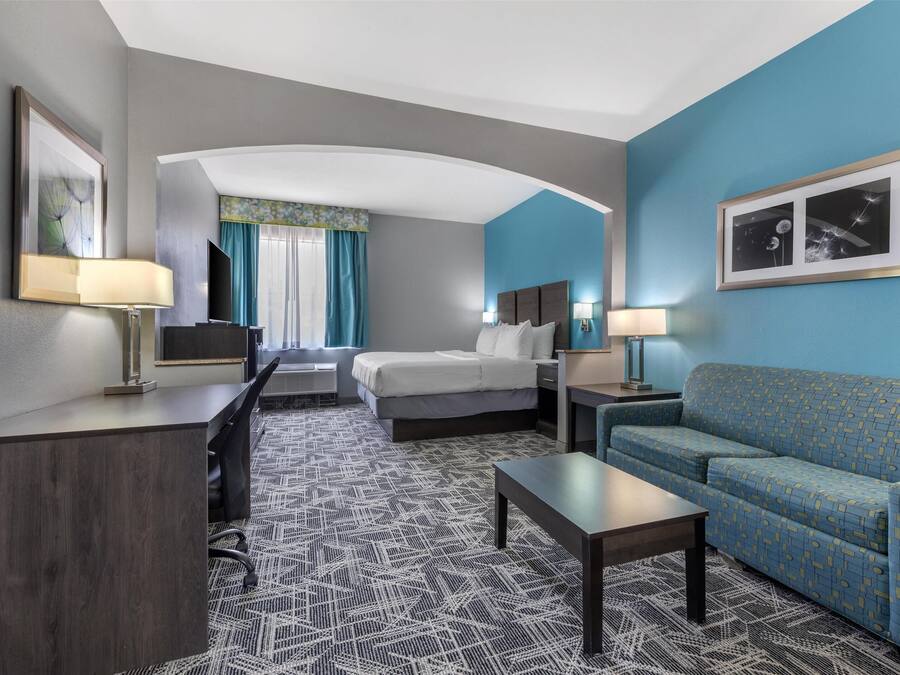 Una habitación de hotel con cama, sofá, escritorio y televisor.