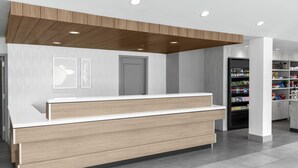 Zona de recepción con mostrador de madera, una puerta y una pared decorada con cuadros.