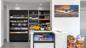 Un espacio comercial moderno con estantes repletos de bebidas, aperitivos y frutas.