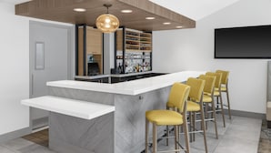 Una cocina moderna con una isla central, taburetes de bar y un armario empotrado para vinos.