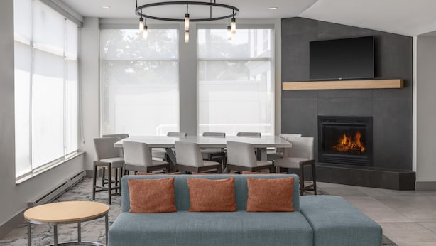 Una sala de estar moderna con un sofá, una chimenea, un comedor y ventanas amplias.