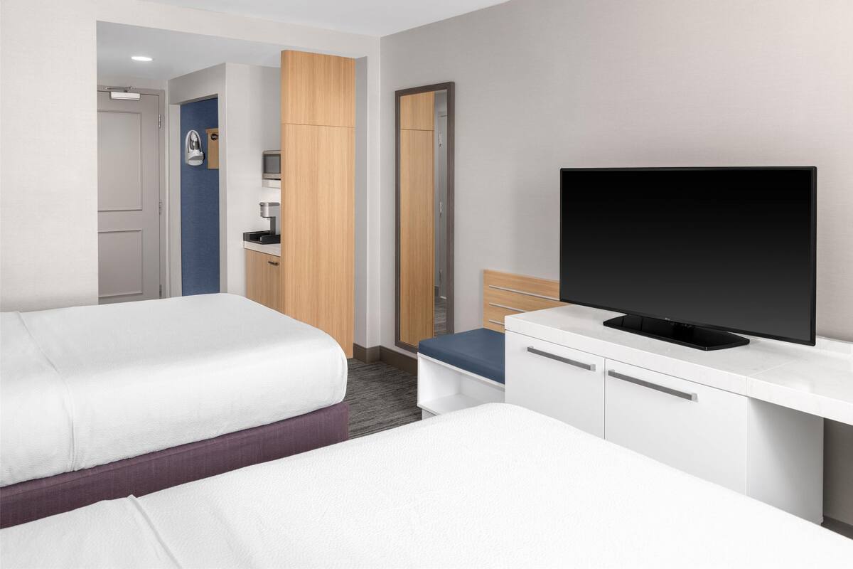 A hotel room with two beds, a TV, a desk, and a wardrobe.
