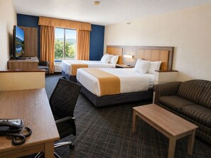 Ein Hotelzimmer mit zwei Betten, einem Schreibtisch, einem Sessel, einer Couch und einem Fernseher.