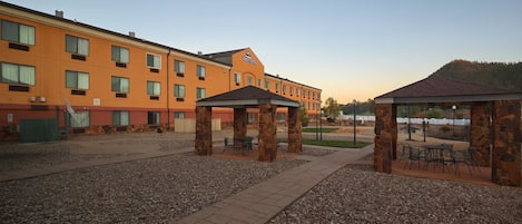 Um pátio de hotel com pilares de pedra, área de estar ao ar livre e um edifício com várias janelas.