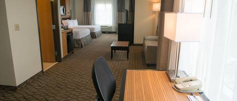 A hotel room with a bed, a desk, a chair, a telephone, and a television.
