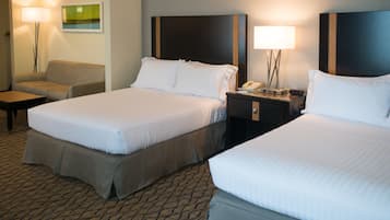 Habitación de hotel con dos camas, un sofá, una mesita de noche con teléfono y una lámpara.