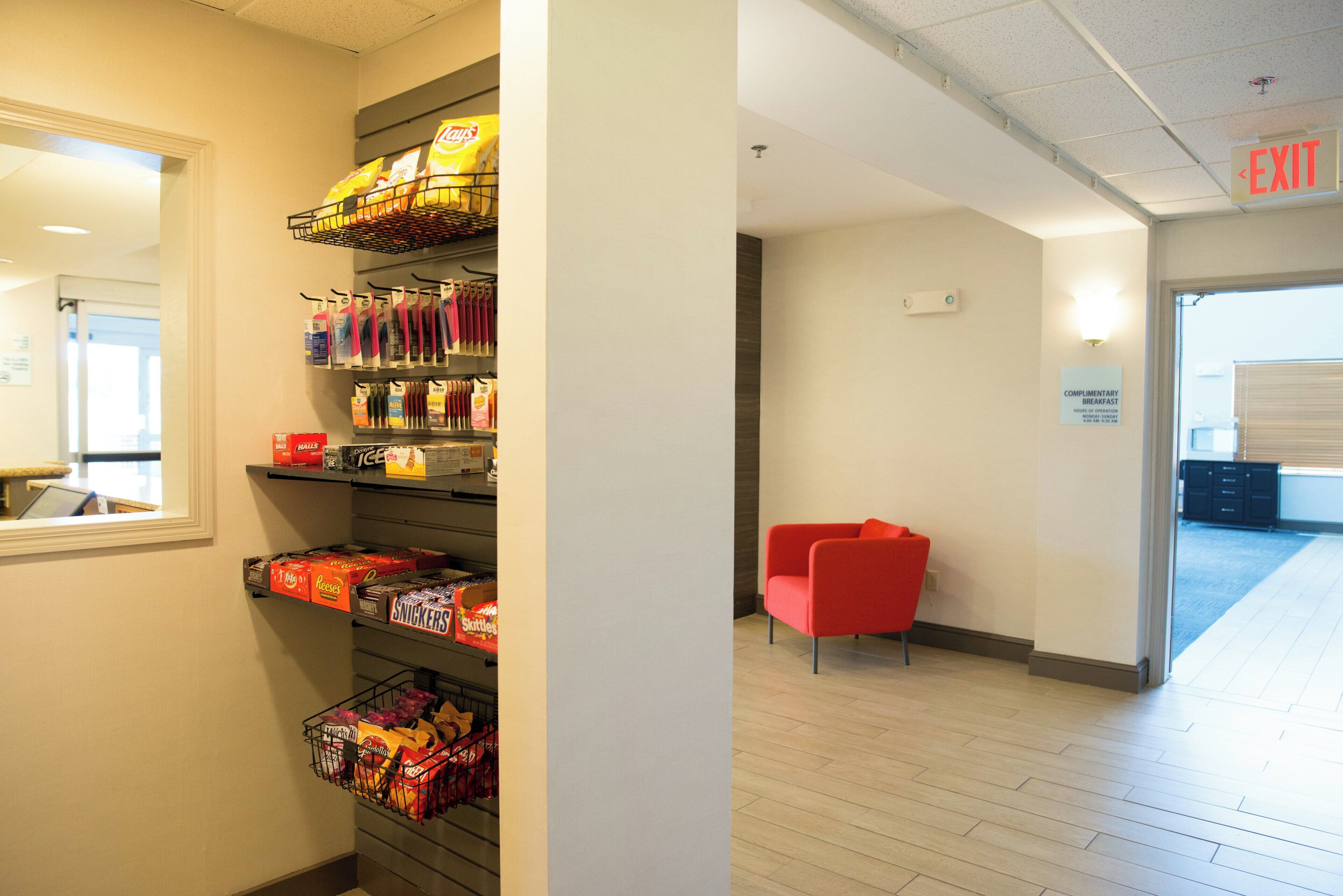 Un bar de aperitivos con diferentes productos envaselados y una silla roja en un pasillo.
