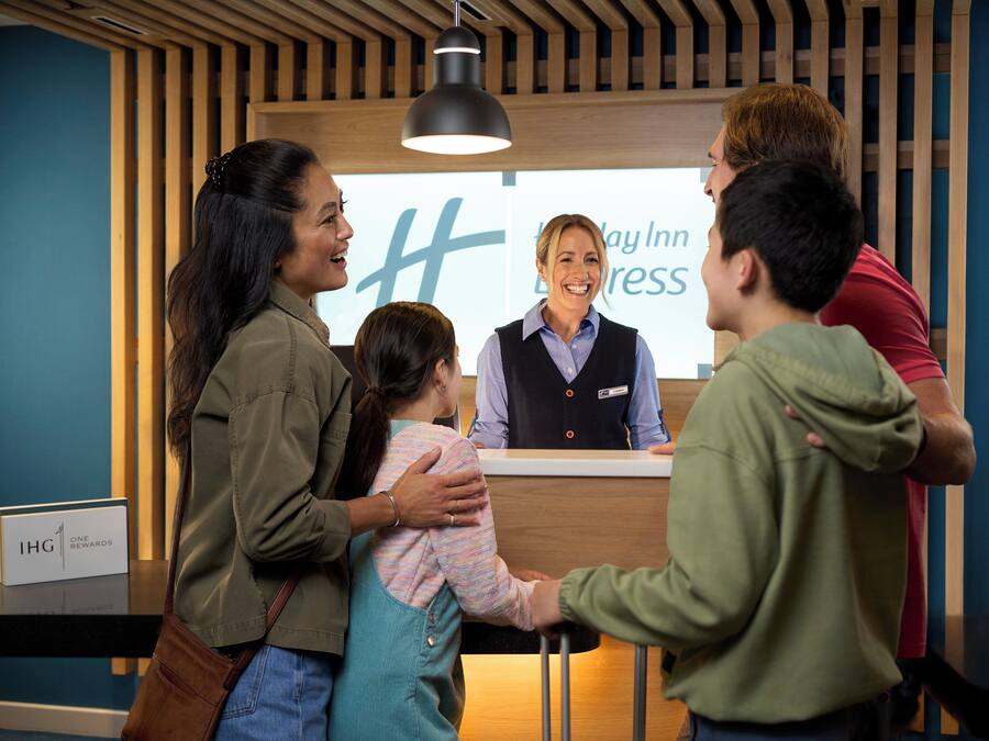 A reception desk with a sign that reads 'Day Inn Express' and a sign indicating 'IHG ONE REWARDS'.