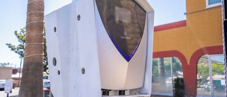 A parking meter with the brand name "LECTRON" on it, mounted on a pole with a clear view of a building with a red and yellow facade in the background.