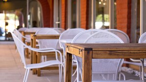 Outdoor seating with white chairs and wooden tables, arranged in rows. - Hotel Americana (Nogales)