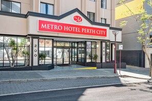 The exterior of the Metro Hotel Perth City with a prominent red sign, large glass entrance, and a modern architectural design.