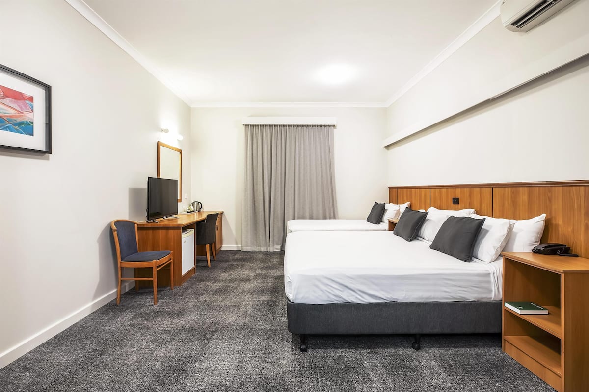 A hotel room with a bed, desk, chair, and a television.