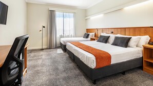A hotel room with a bed, two bedside tables, a desk, a chair, and a window with curtains. - Metro Hotel Perth City (East Perth)