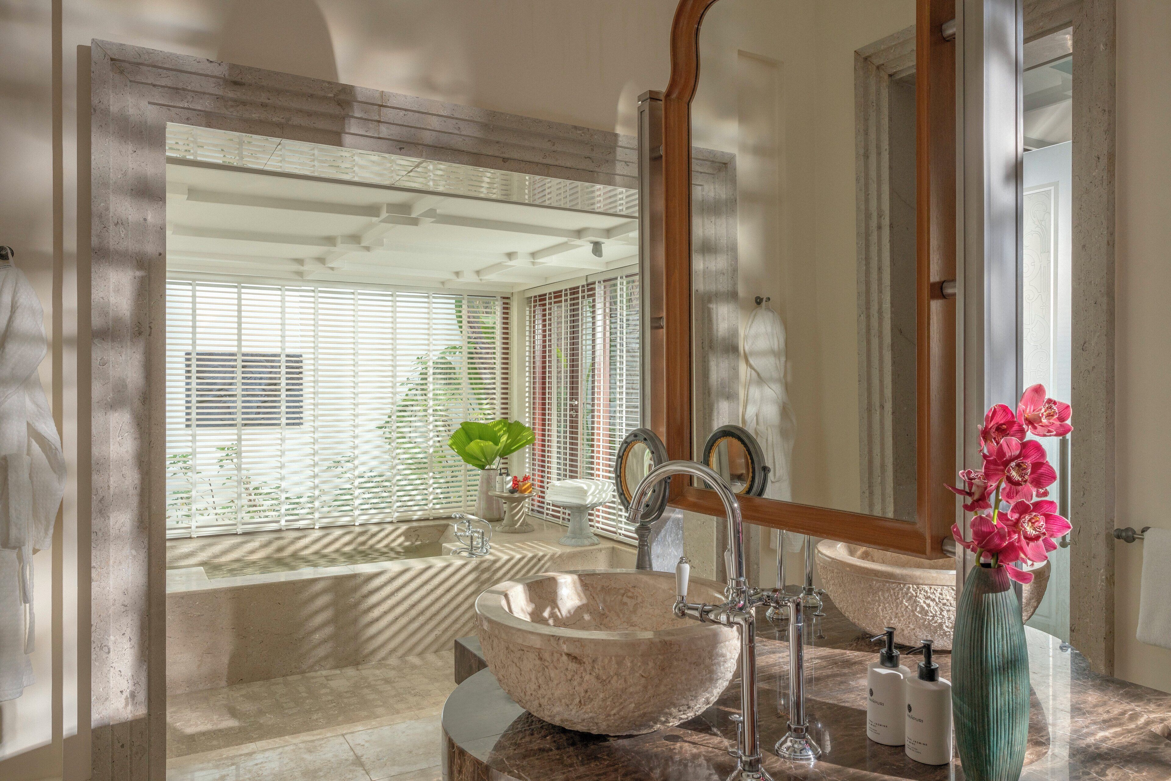 A bathroom with a large stone sink, a bathtub, and a mirror.