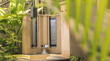 A stone fountain with a tiled mosaic window, surrounded by greenery.